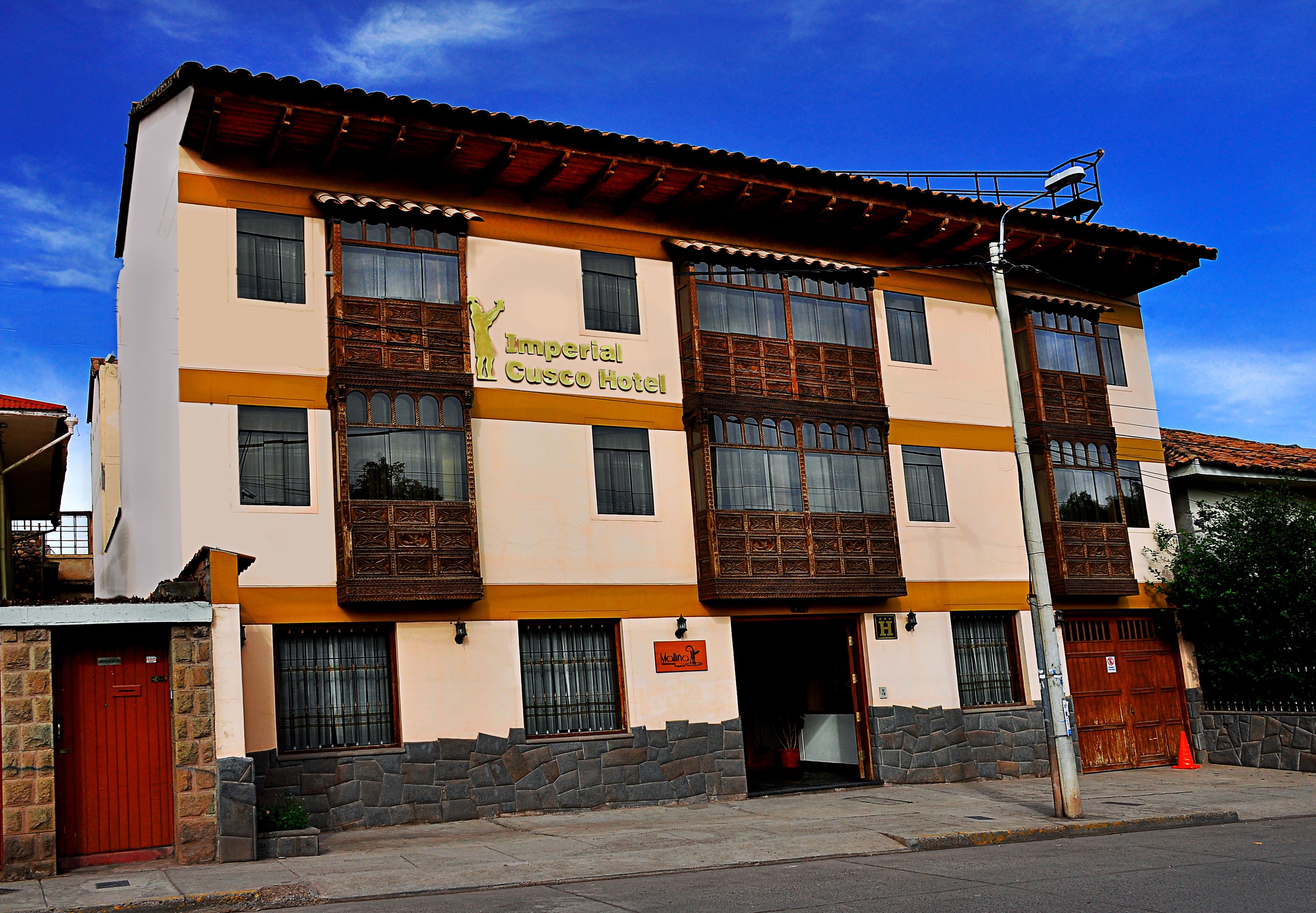 A two-story building with a sign for the Imperial Cusco Hotel.
