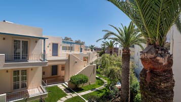 Edifício residencial com várias varandas, um jardim bem cuidado e palmeiras.