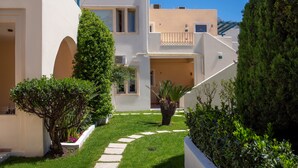 Un edificio moderno con fachada blanca, un patio central con un sendero y un pequeño árbol.