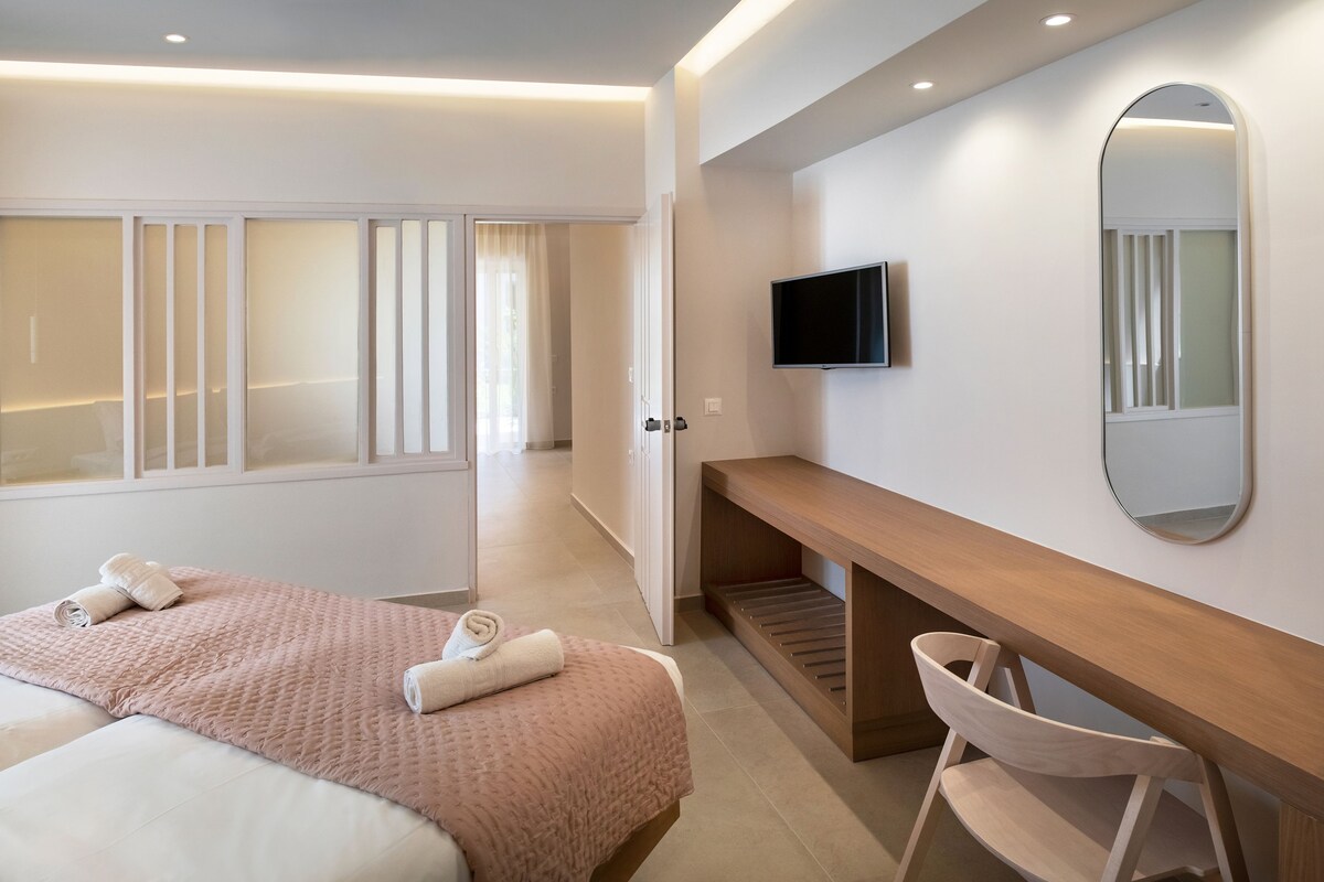 Une chambre d’hôtel moderne équipée d’un lit, d’un bureau, d’une chaise, d’une télévision et d’un grand miroir.