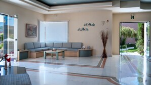 Eine moderne Lobby mit einer Eckcouch, einem Couchtisch und einer Glastür, die nach draußen führt.