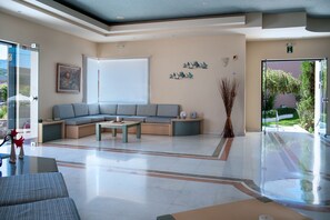 A modern lobby with a sectional sofa, a coffee table, and a glass door leading outside.