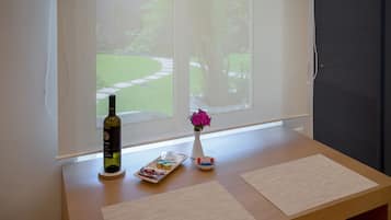 A wooden table with a bottle, a vase with flowers, and a tray with food items.