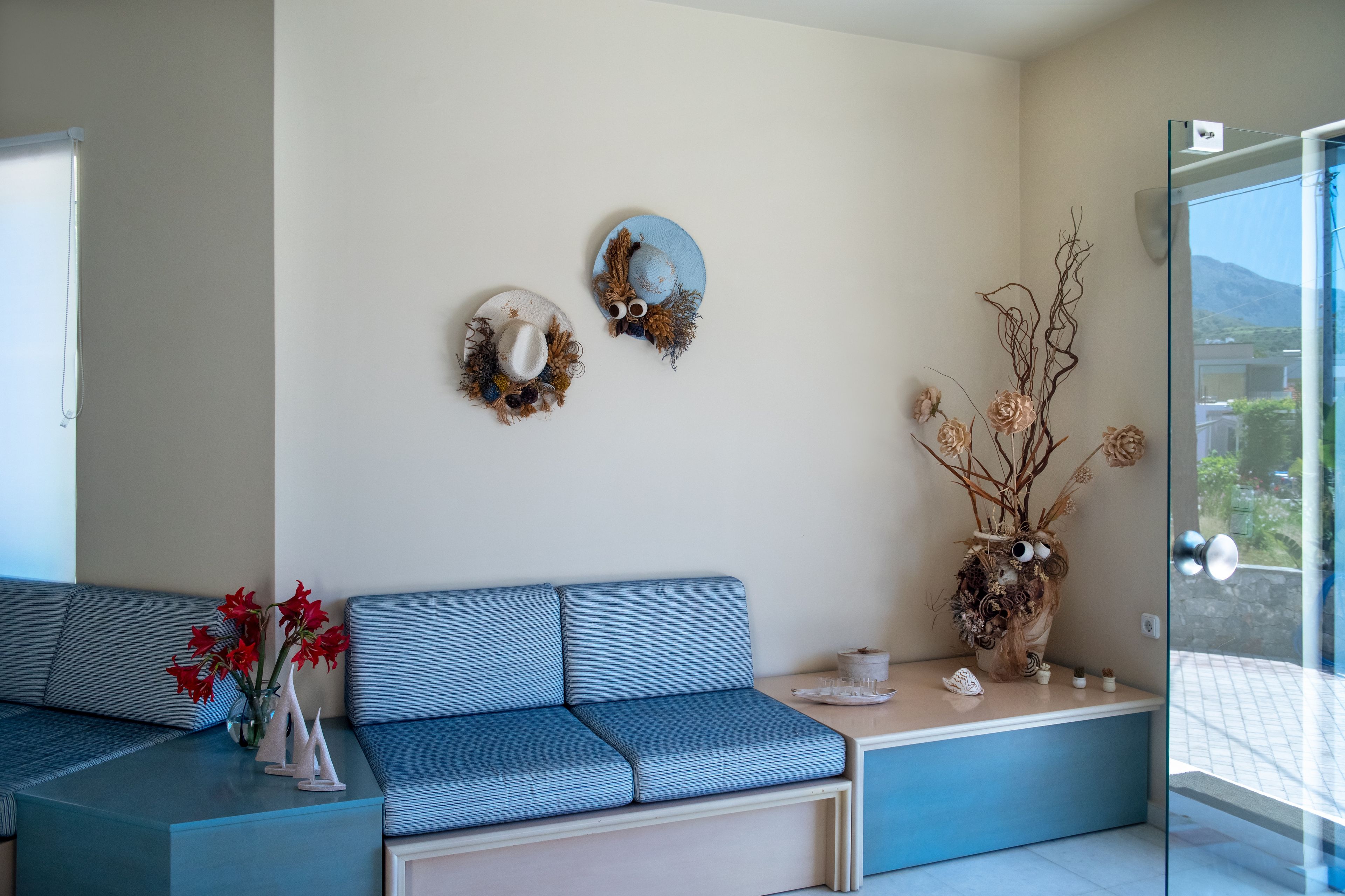 A modern living room with a blue sofa, a glass coffee table, and two wall-mounted decorative items.