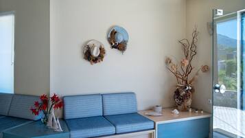 A modern living room with a blue sofa, a glass coffee table, and two wall-mounted decorative items.