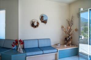Una sala de estar moderna con un sofá azul, una mesa de centro de vidrio y dos elementos decorativos colgados en la pared.