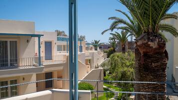 A multi-story residential building with balconies, a palm tree, and a clear sky.