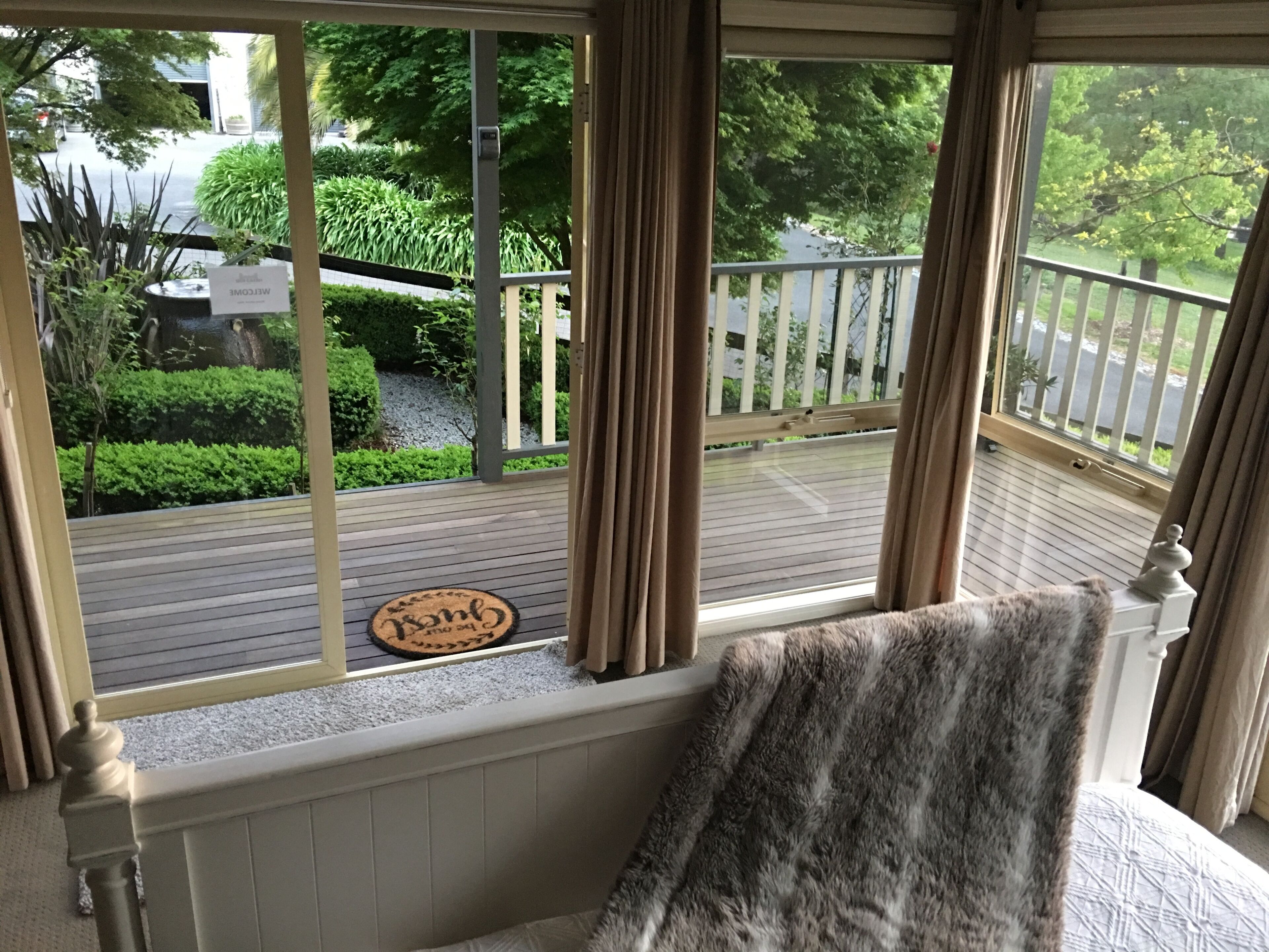 Ein Zimmer mit Blick auf eine Holzterrasse und grüne Bepflanzung.