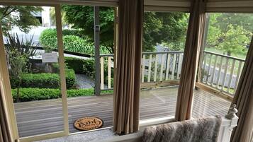 Ein Zimmer mit Blick auf eine Holzterrasse und grüne Bepflanzung.