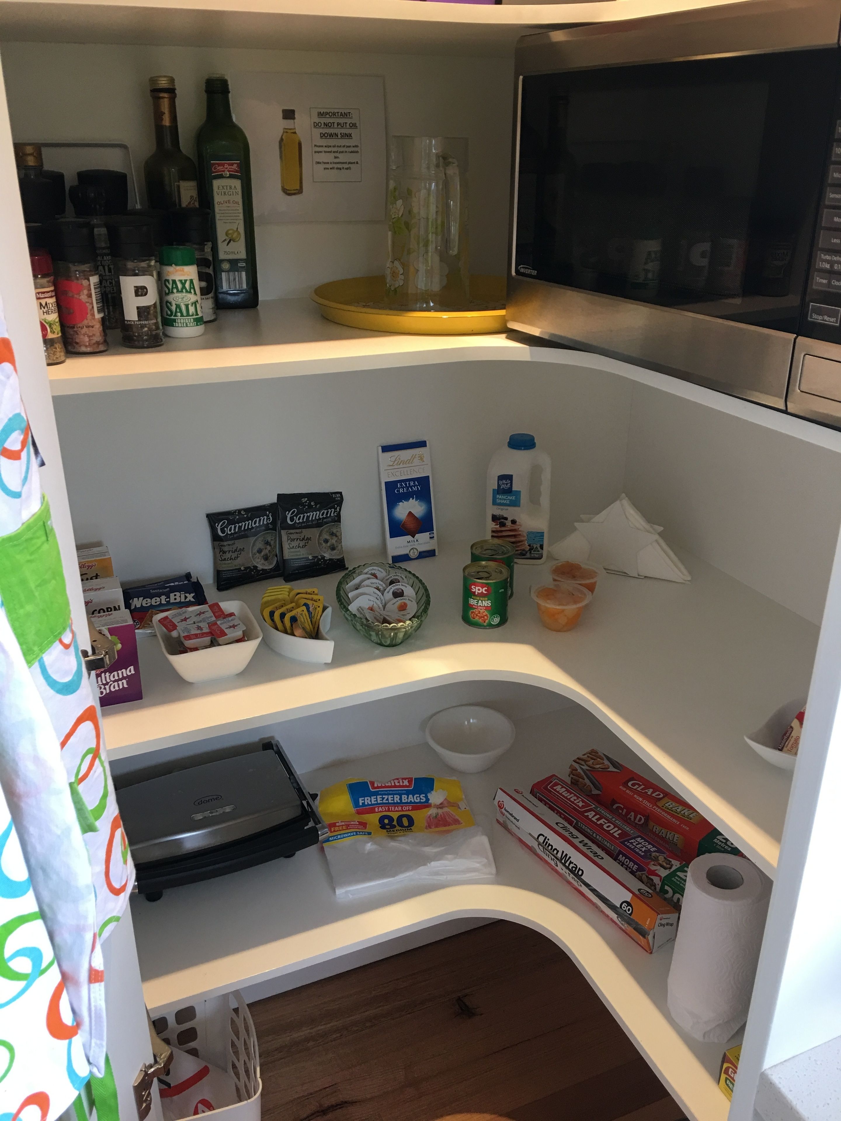 Eine Küche mit Mikrowelle, Regalen voller Lebensmittel und einem Kühlschrank.