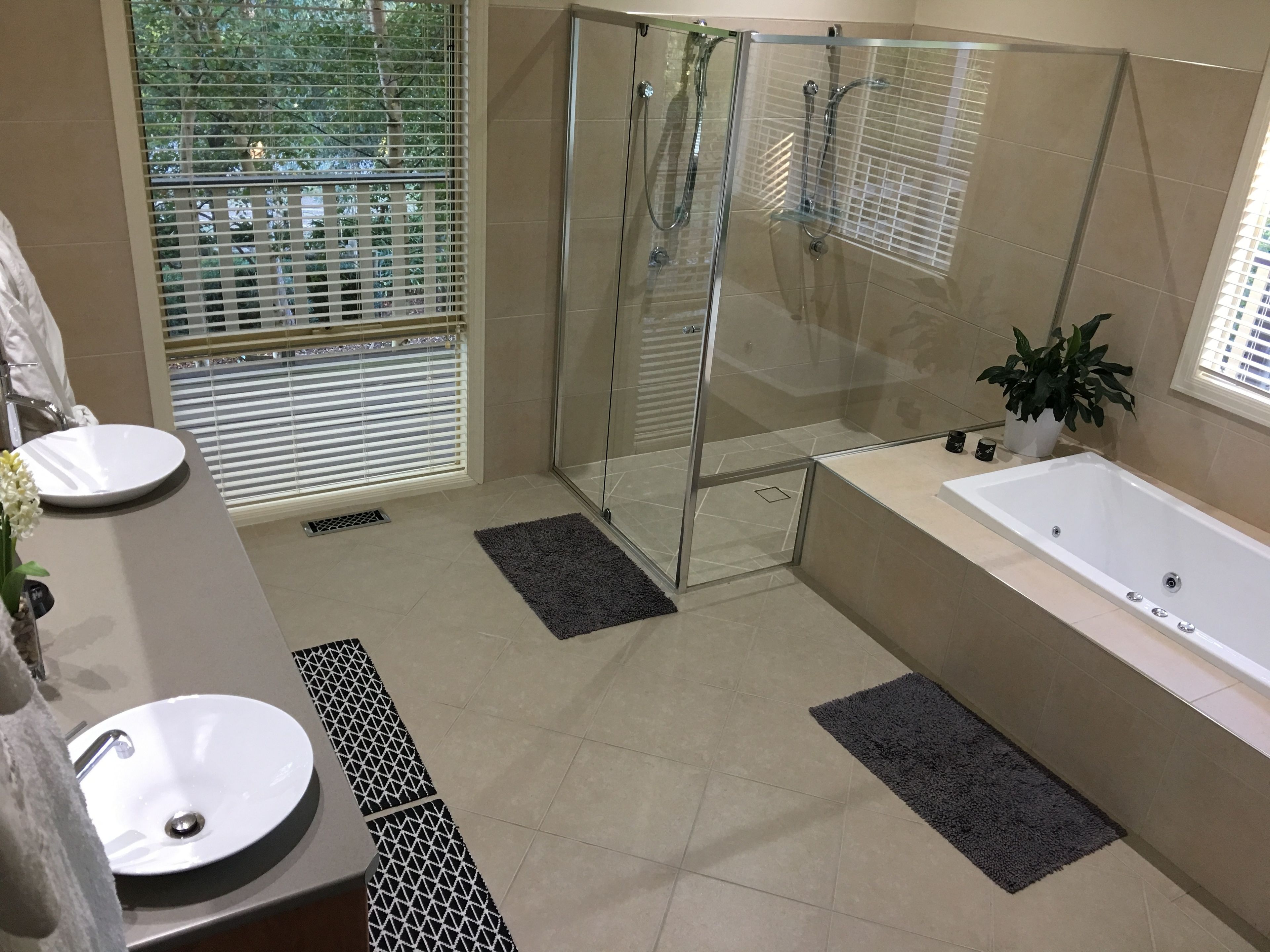 Ein modernes Badezimmer mit einer Duschkabine, zwei Waschbecken, einer Badewanne und einem Blumentopf.