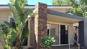 A modern house with a stone pillar, a staircase, and large green plants. - Emerald Ridge (Emerald)