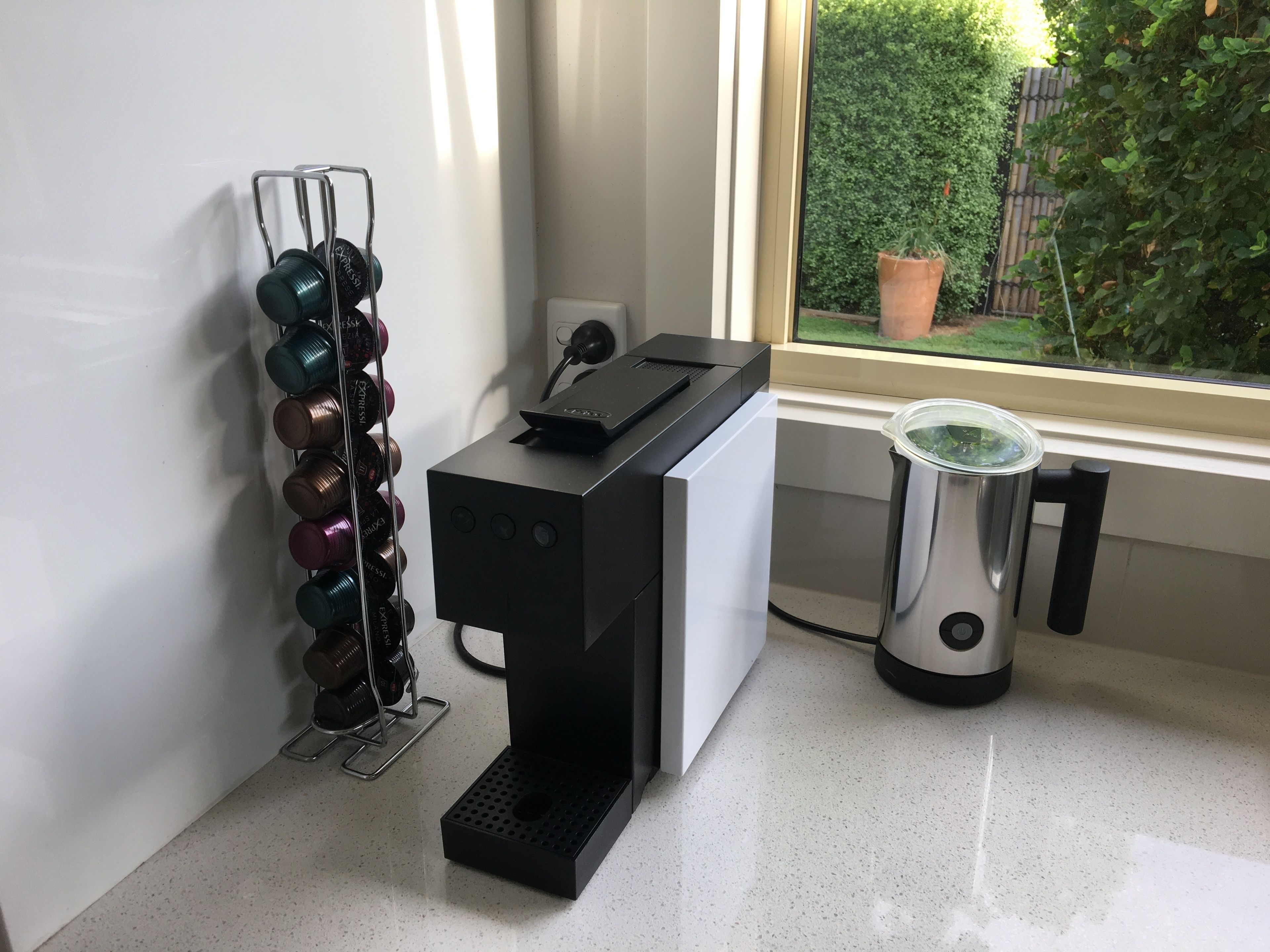 A coffee machine, a kettle, and a wine rack by a window.