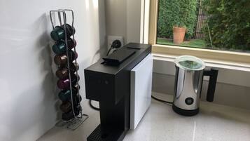 A coffee machine, a kettle, and a wine rack by a window.