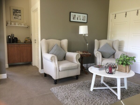 A living room with two armchairs, a coffee table, a lamp, and a bookshelf. - Emerald Ridge (Emerald)
