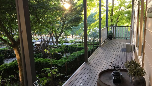 A wooden deck with a metal railing, surrounded by lush greenery and trees. - Emerald Ridge (Emerald)