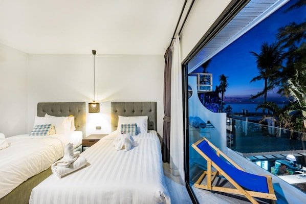 A hotel room with two beds, a large window with a view of the pool and palm trees, and a chair by the window. - Thai Kamala Beach Front (Kamala)