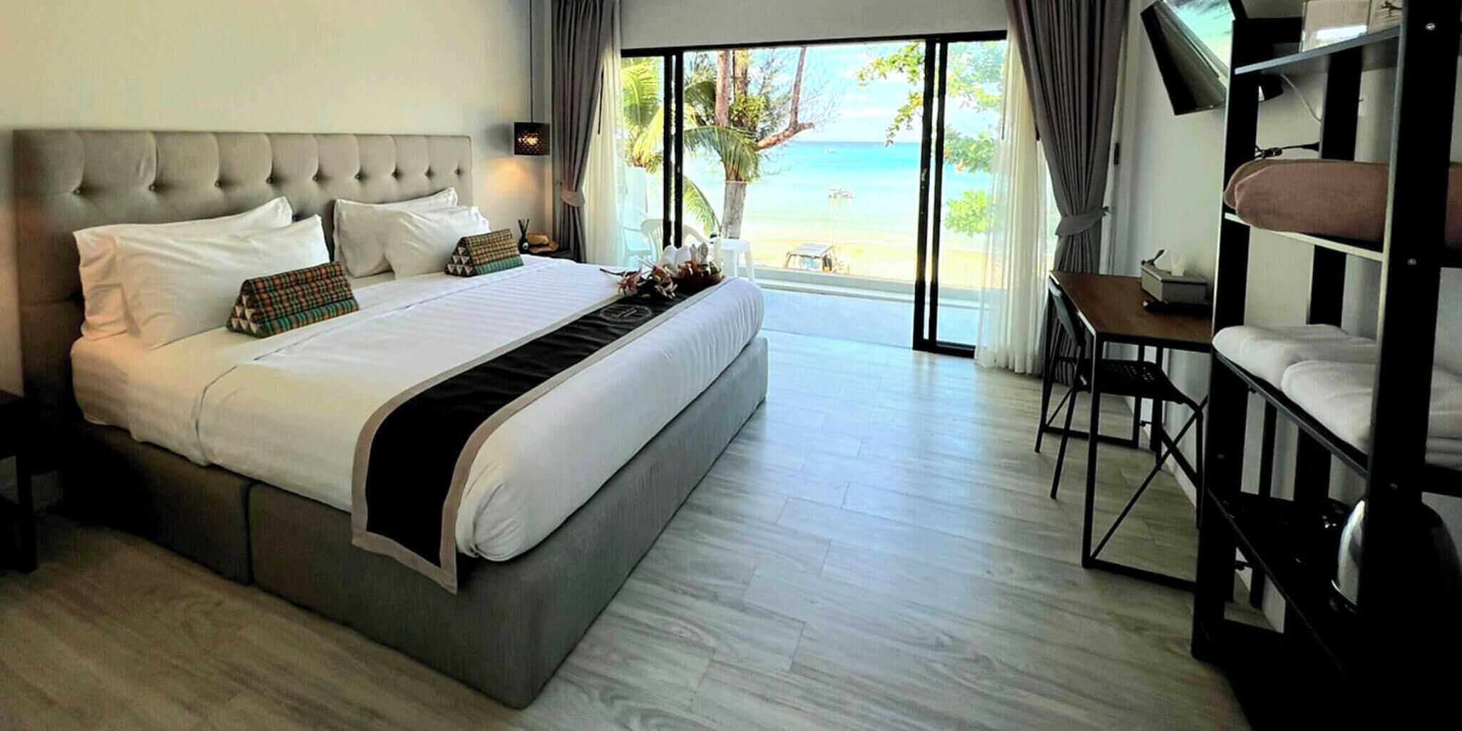 Una habitación de hotel con una cama grande, un escritorio y vistas a la playa.