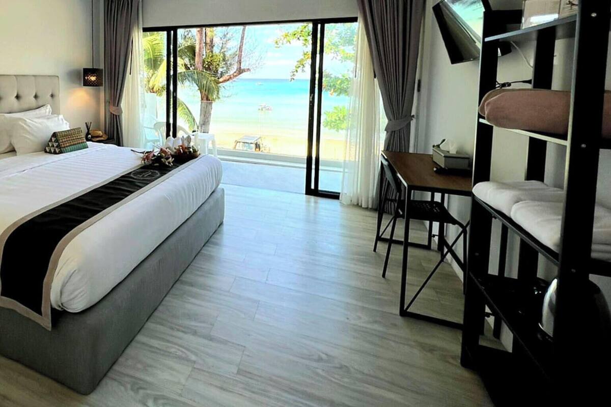 Quarto de hotel com uma cama grande, uma escrivaninha e vista para a praia.