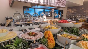 A buffet with various food items and a tropical plant in the foreground. - Hotel Clover Patong Phuket (Patong)