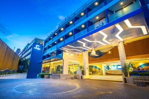 Un hotel moderno con una estructura de varios niveles, una recepción destacada y una amplia entrada exterior.