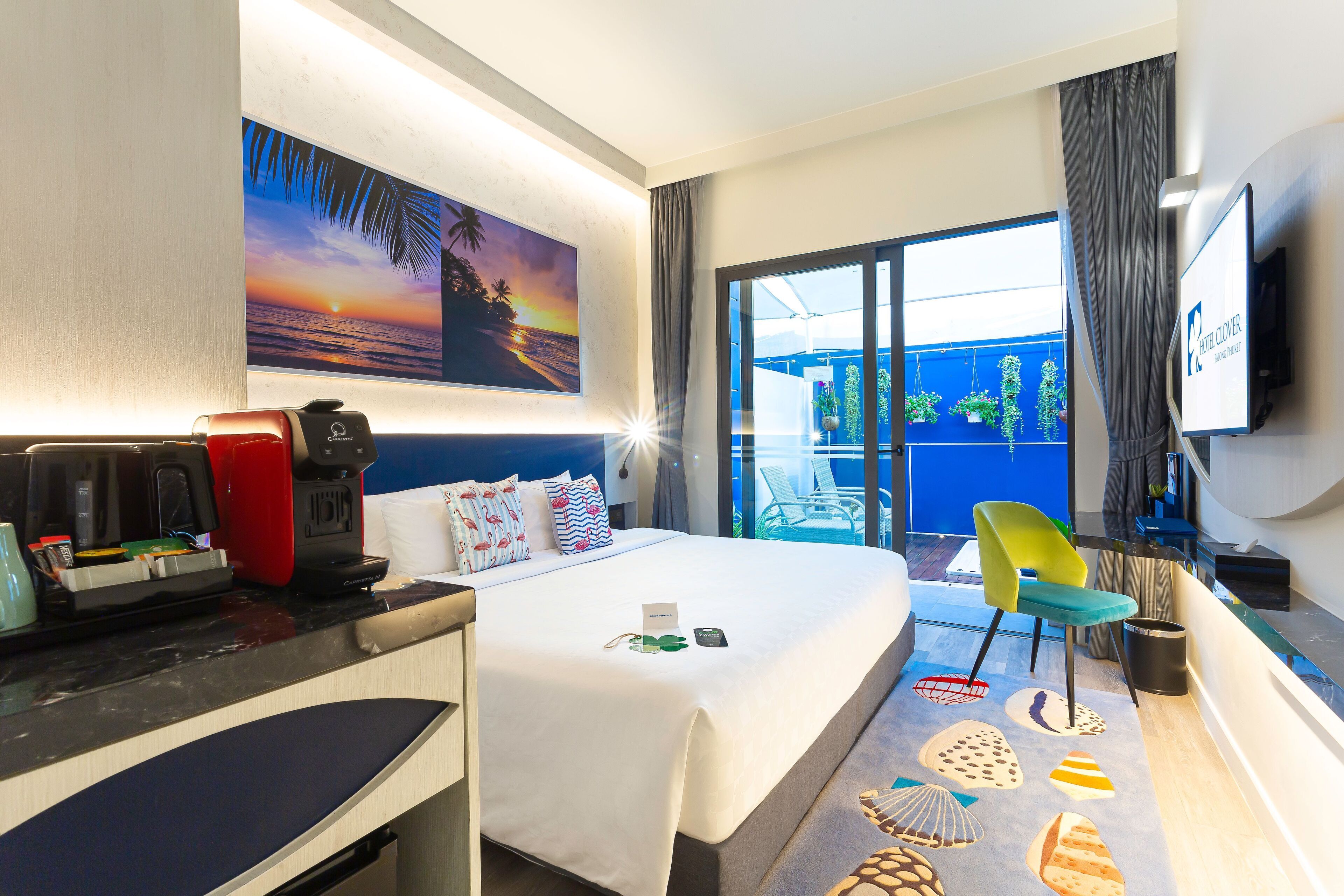 A hotel room with a bed, a desk with a coffee maker, a TV, and a view of the outside balcony.