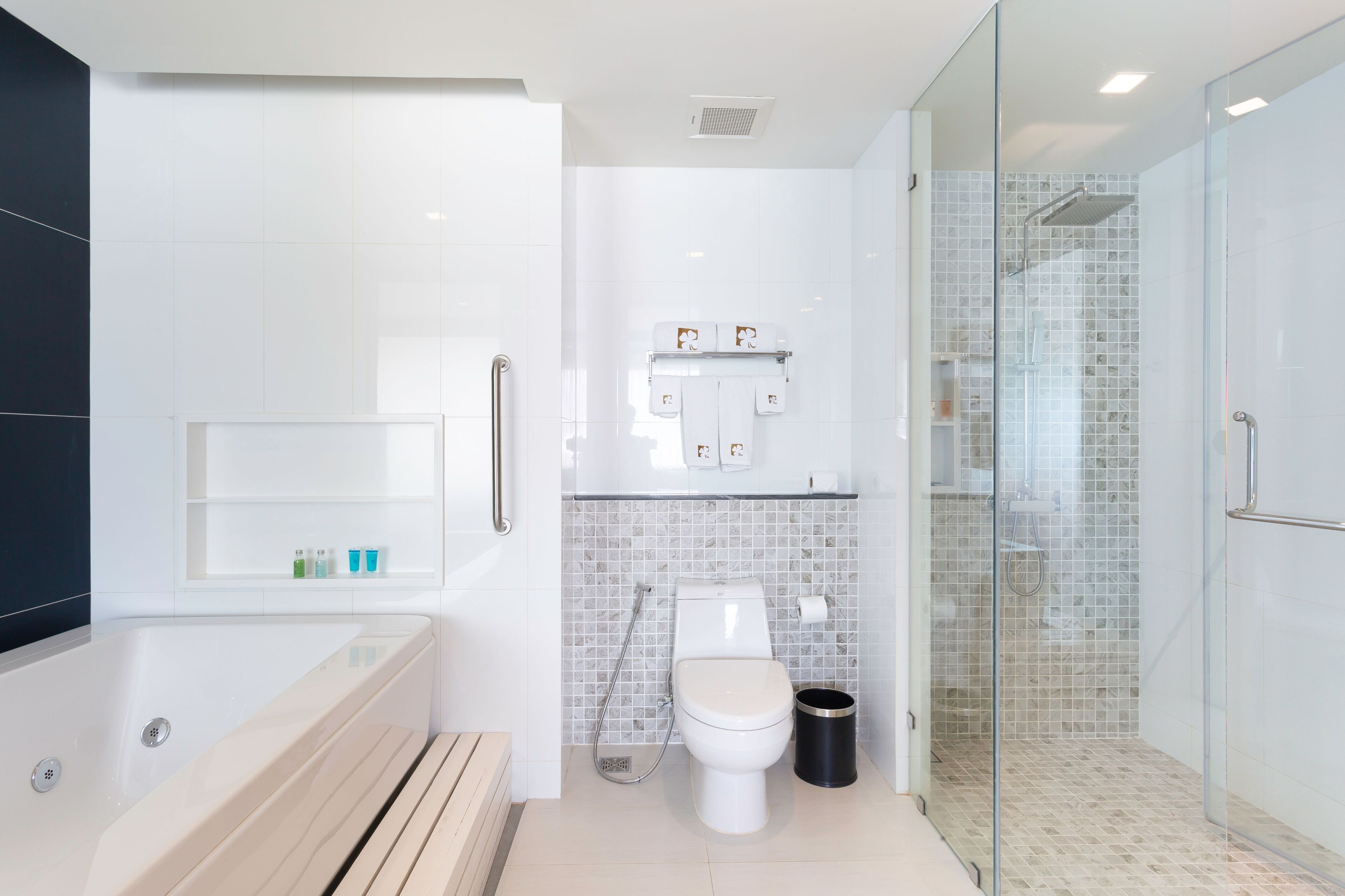 A modern bathroom with a bathtub, toilet, and glass-enclosed shower.