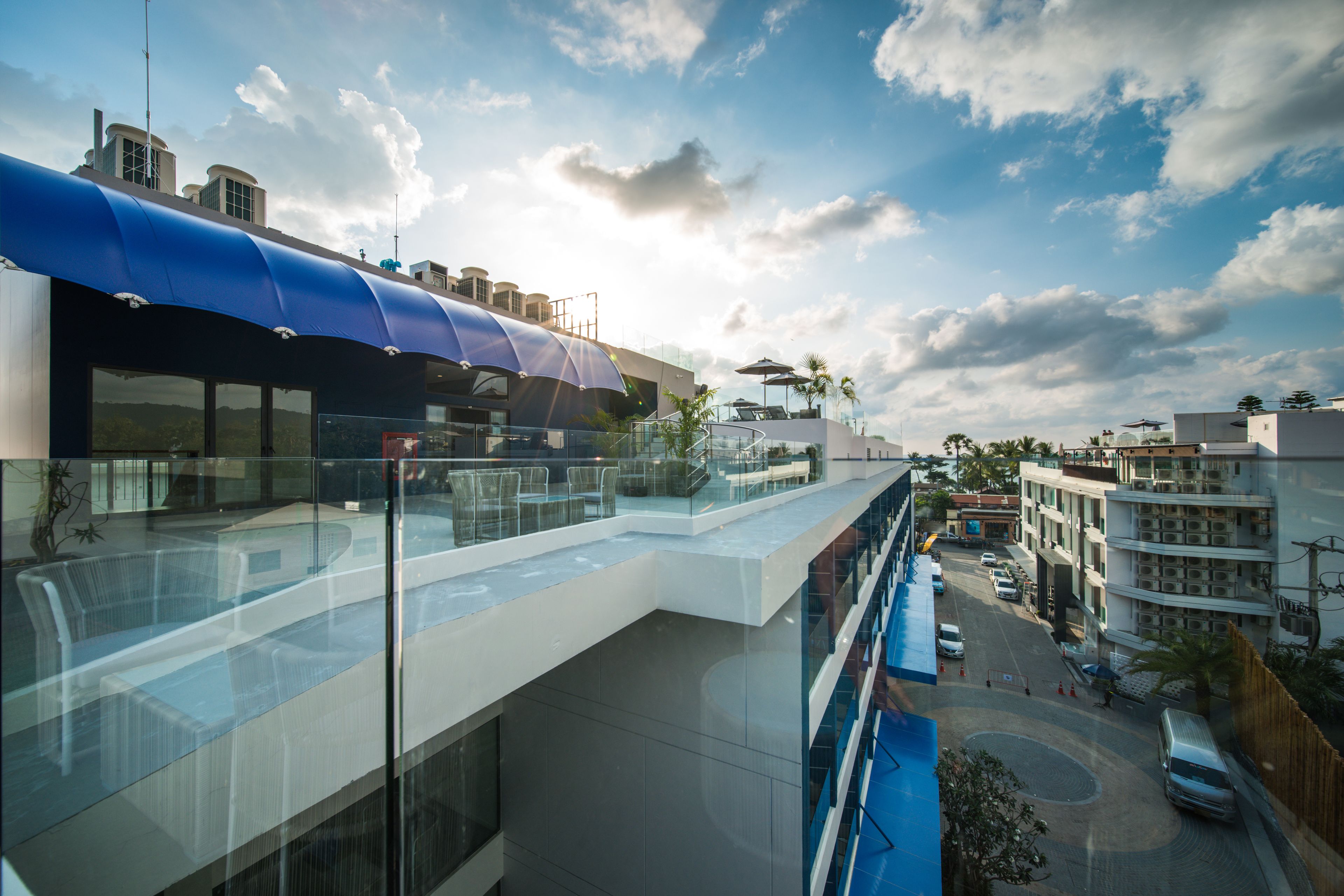 Un bâtiment moderne doté d’une façade en verre, d’un auvent bleu et d’une terrasse sur le toit.