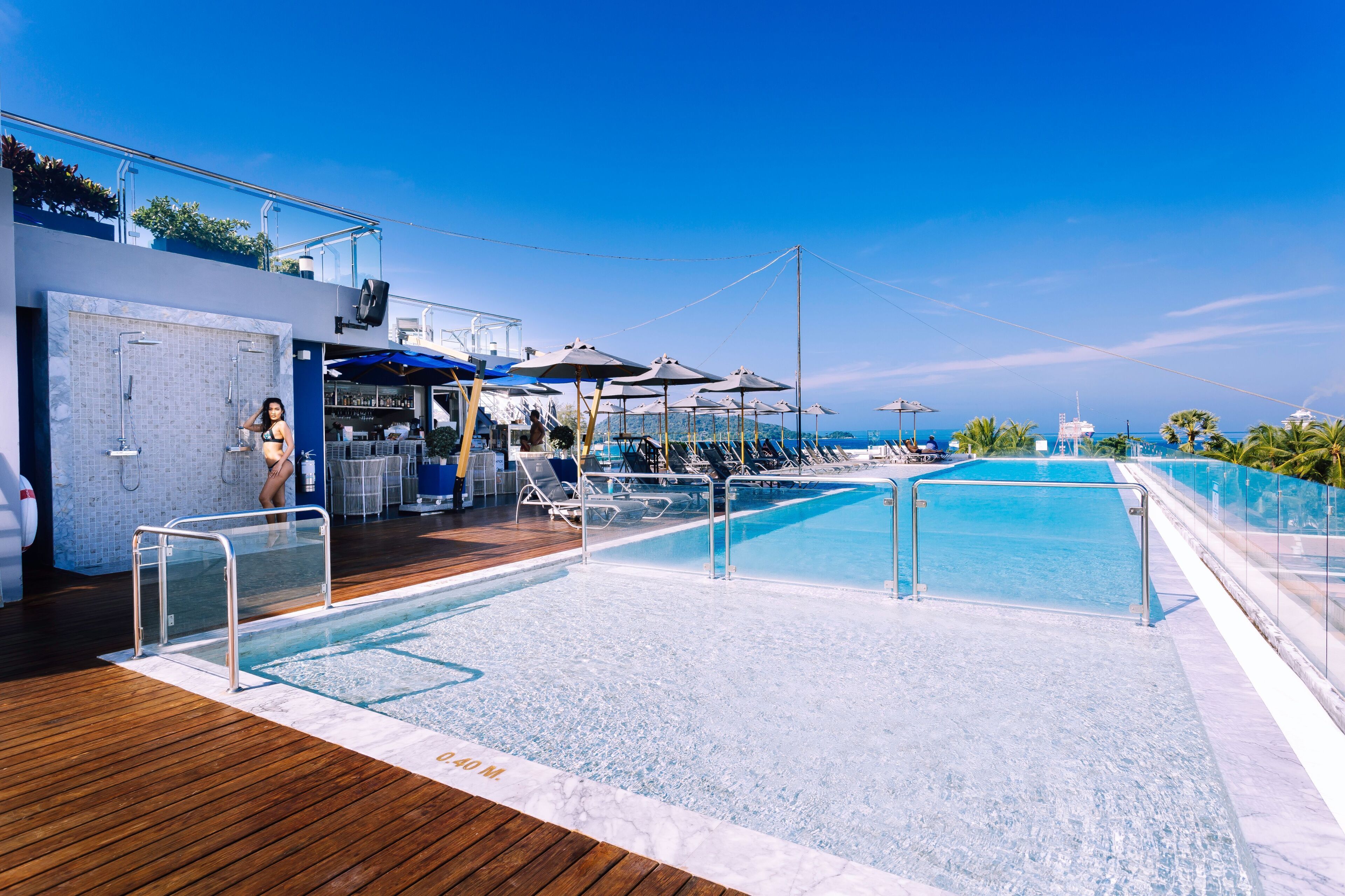 Een zwembadgedeelte met ligbedden, parasols, een bar en uitzicht op de oceaan.