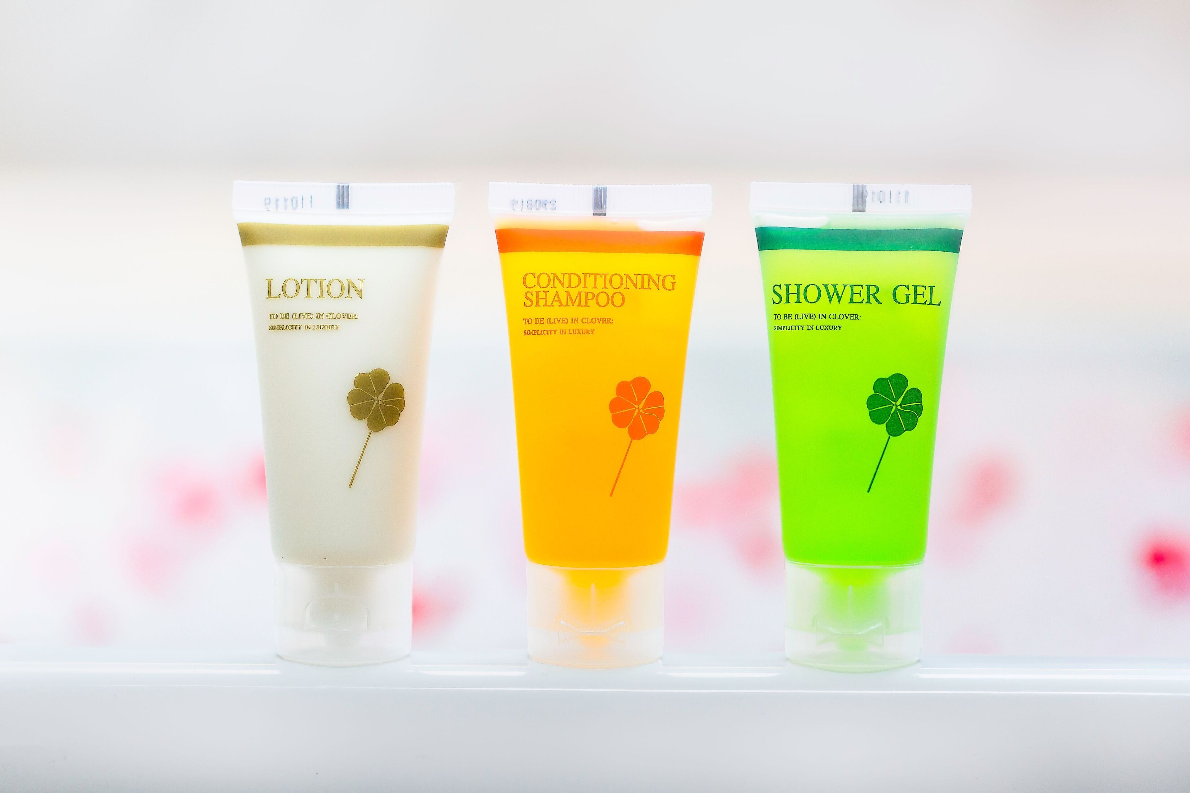 Three tubes of lotion, conditioner, and shower gel with clover designs.