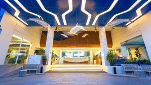 A modern hotel lobby with a reception desk, seating area, and decorative ceiling lights. - Hotel Clover Patong Phuket (Patong)