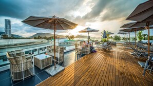 A rooftop terrace with wooden flooring, outdoor seating, and umbrellas. - Hotel Clover Patong Phuket (Patong)