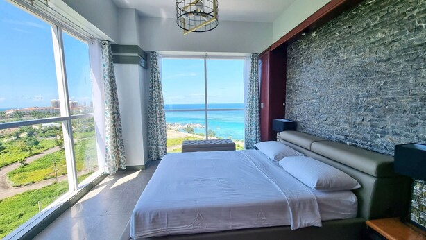 Un dormitorio con un ventanal que ofrece vistas al mar y a la vegetación.