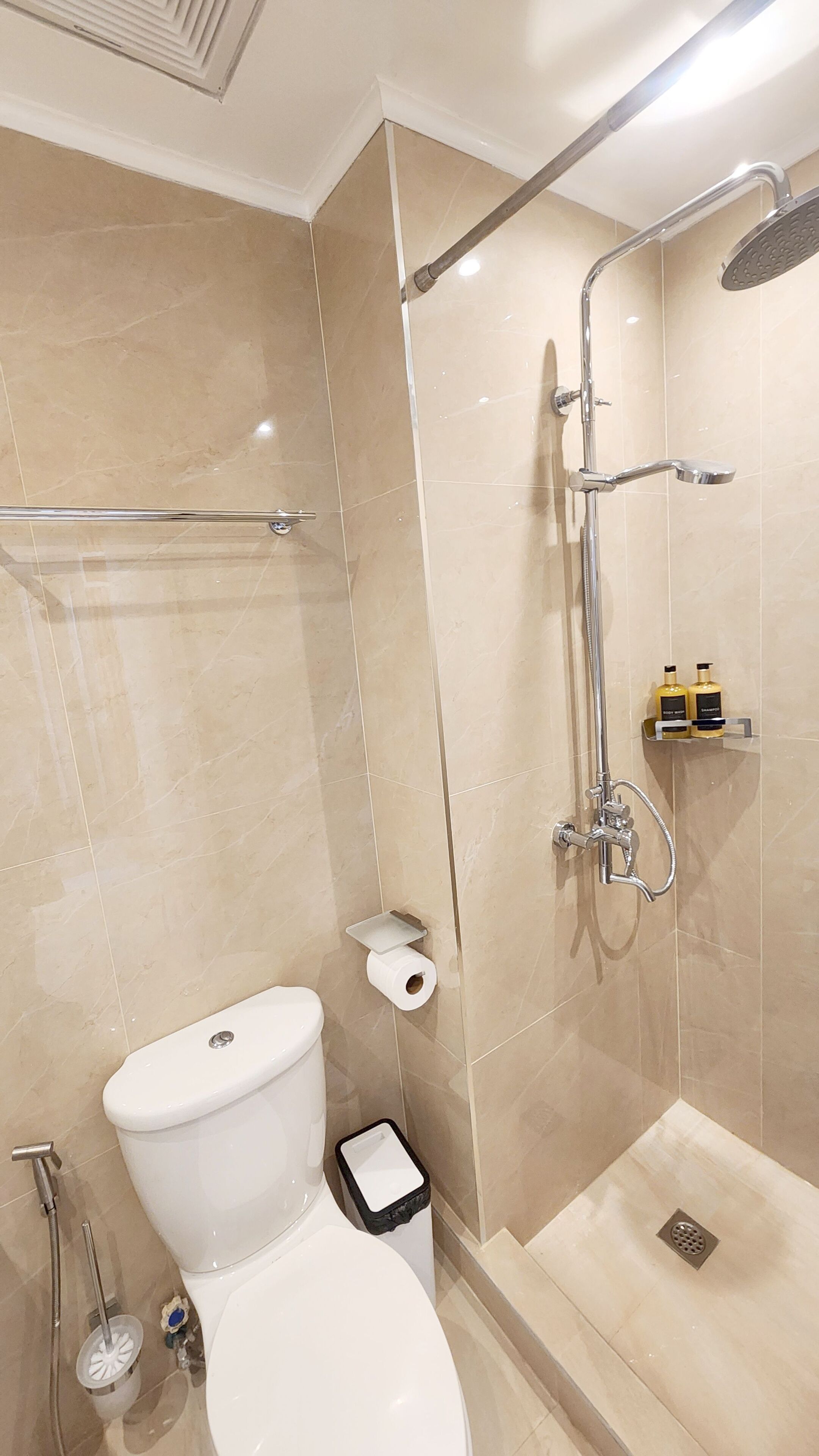 A modern bathroom with a toilet, bidet, shower, and toilet paper holder.