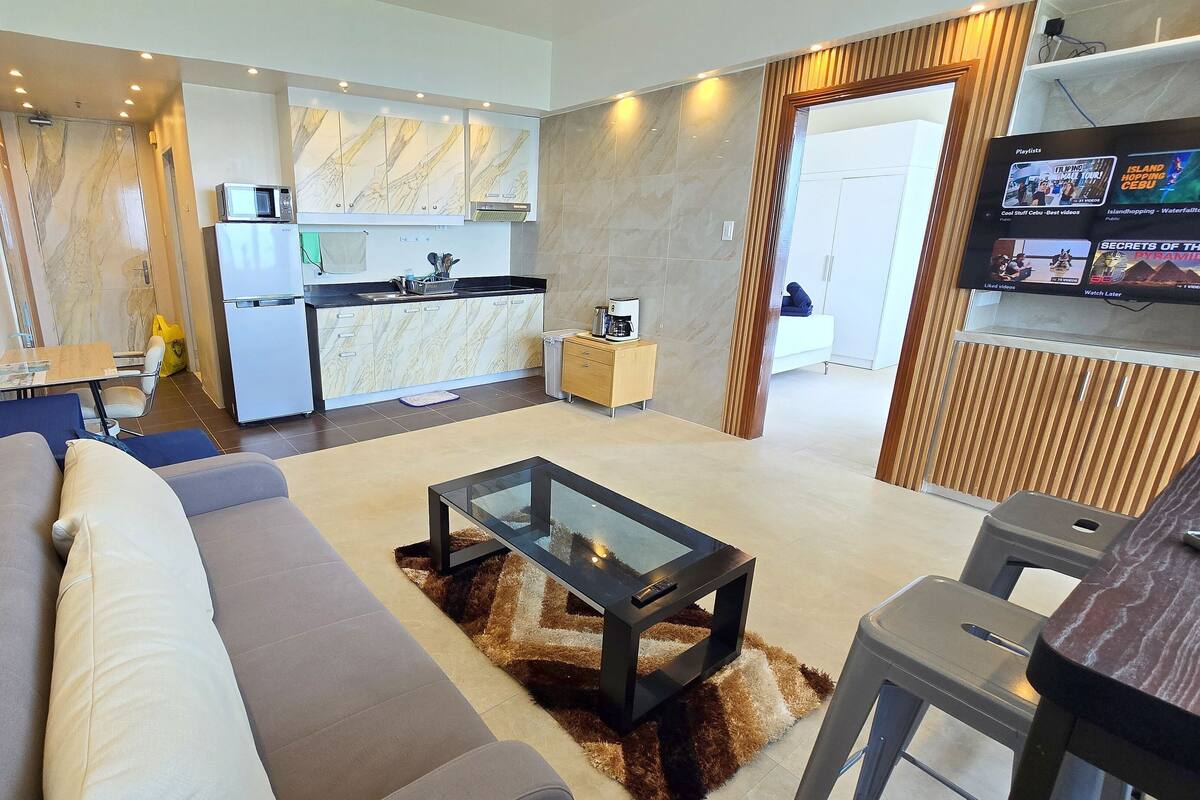 A modern living room with a sofa, a glass coffee table, and a TV.