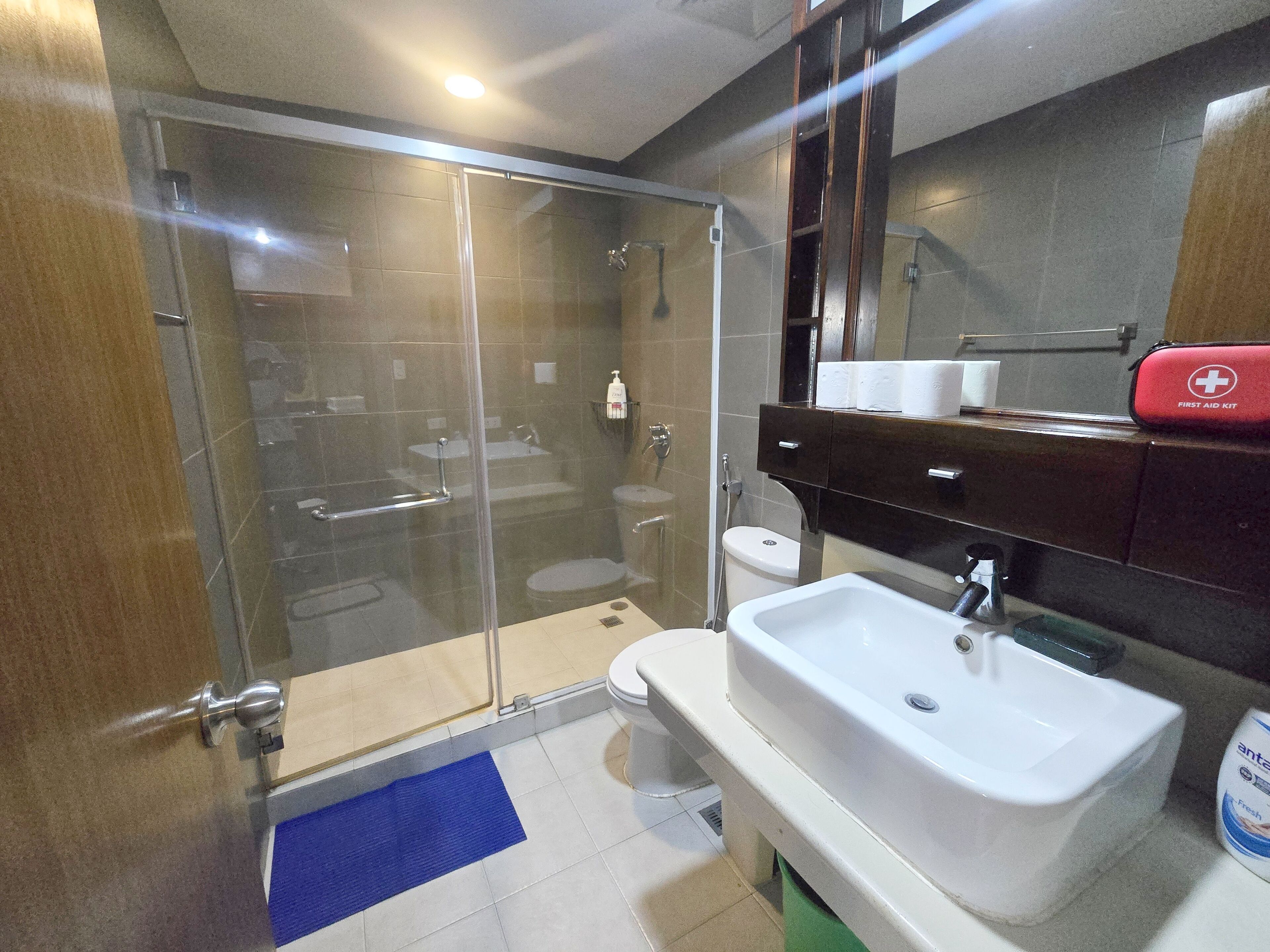 Een moderne badkamer met een douchecabine van glas, een wit wastafelmeubel en een toilet.