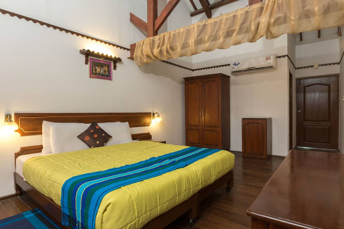 A bedroom with a wooden bed, a nightstand, a wardrobe, and a desk.