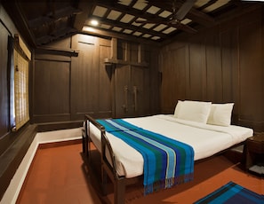 A bedroom with a bed, wooden walls, a ceiling fan, and a window with blinds. - Green Meadows Resort (Chennai)