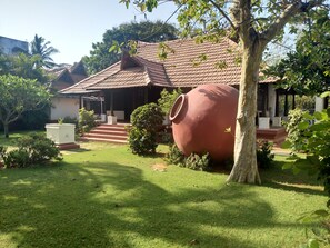 A traditional house with a tiled roof, a large clay pot, and a well-maintained garden. - Green Meadows Resort (Chennai)