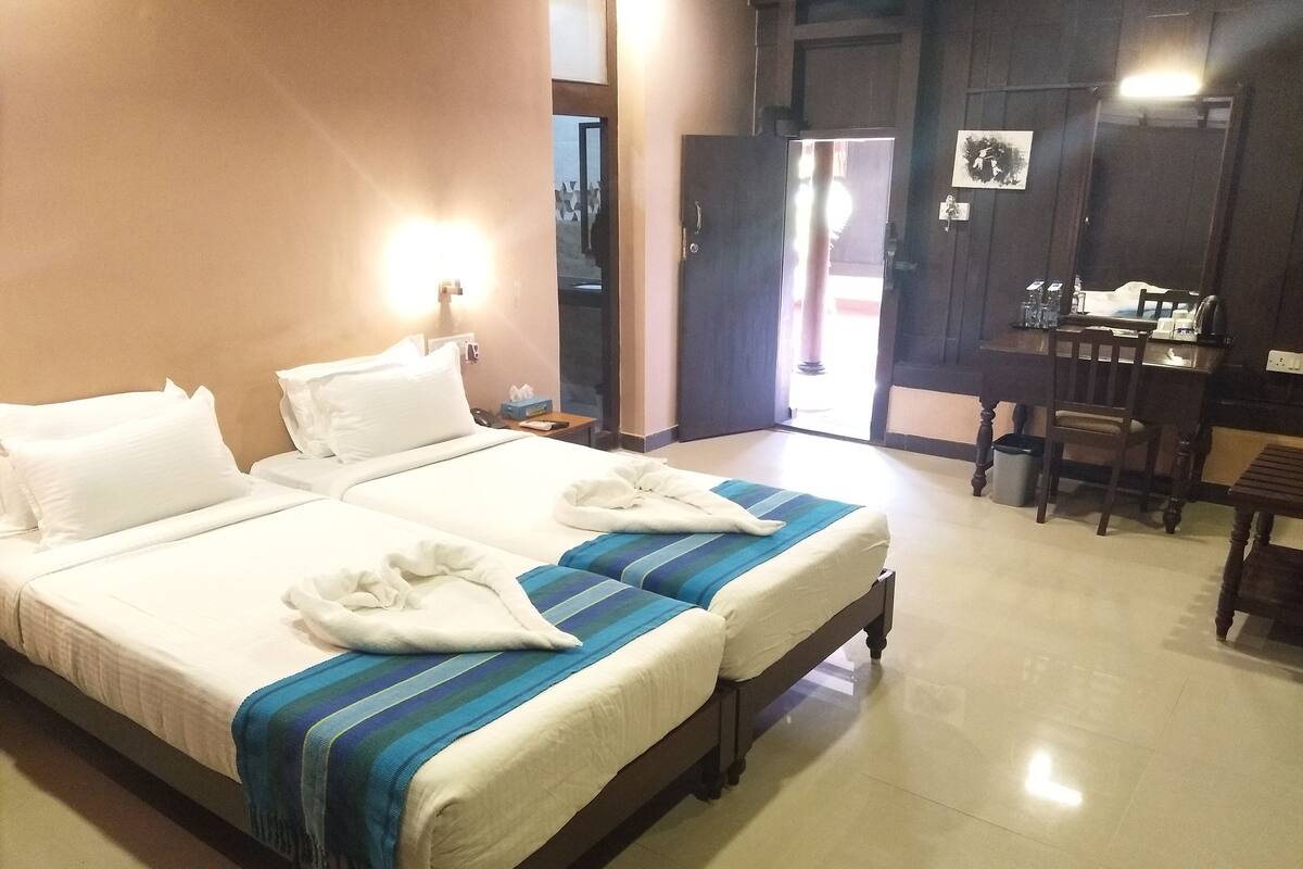 A hotel room with two beds, a desk, and a chair.