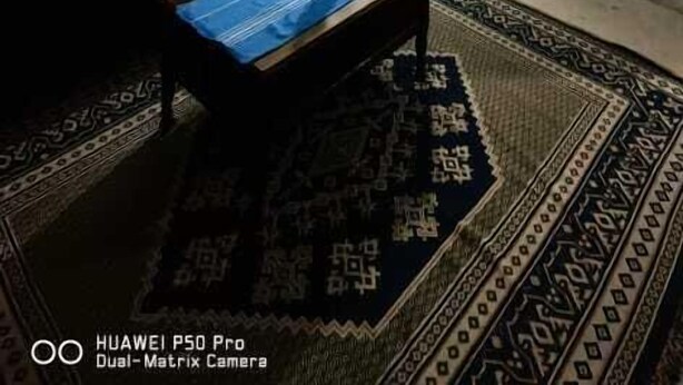 A living room with a blue sofa, a patterned rug, a painting, and a fireplace. - Dar Kenza Tunis (Tunis)
