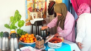 A table with food items and a kettle, surrounded by people. - Dar Kenza Tunis (Tunis)