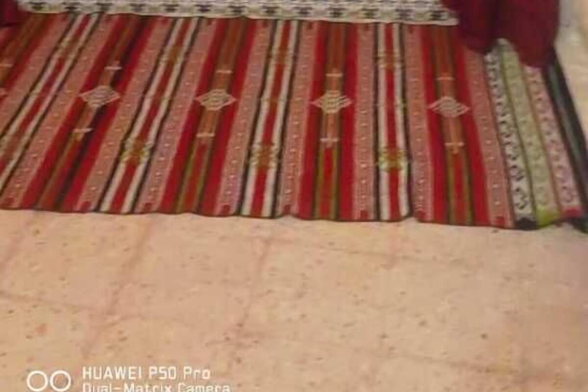 A room with a bed, red curtains, and a patterned rug.
