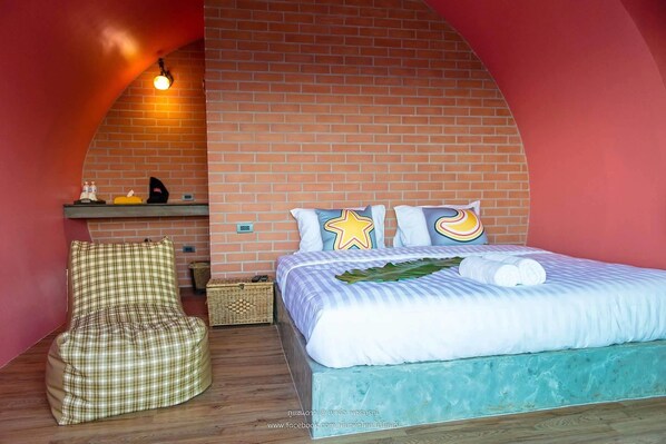 A cozy bedroom with a brick wall, a bed with white bedding, a checkered chair, and a small shelf with items. - Phu Sandao Resort (Khao Kho)