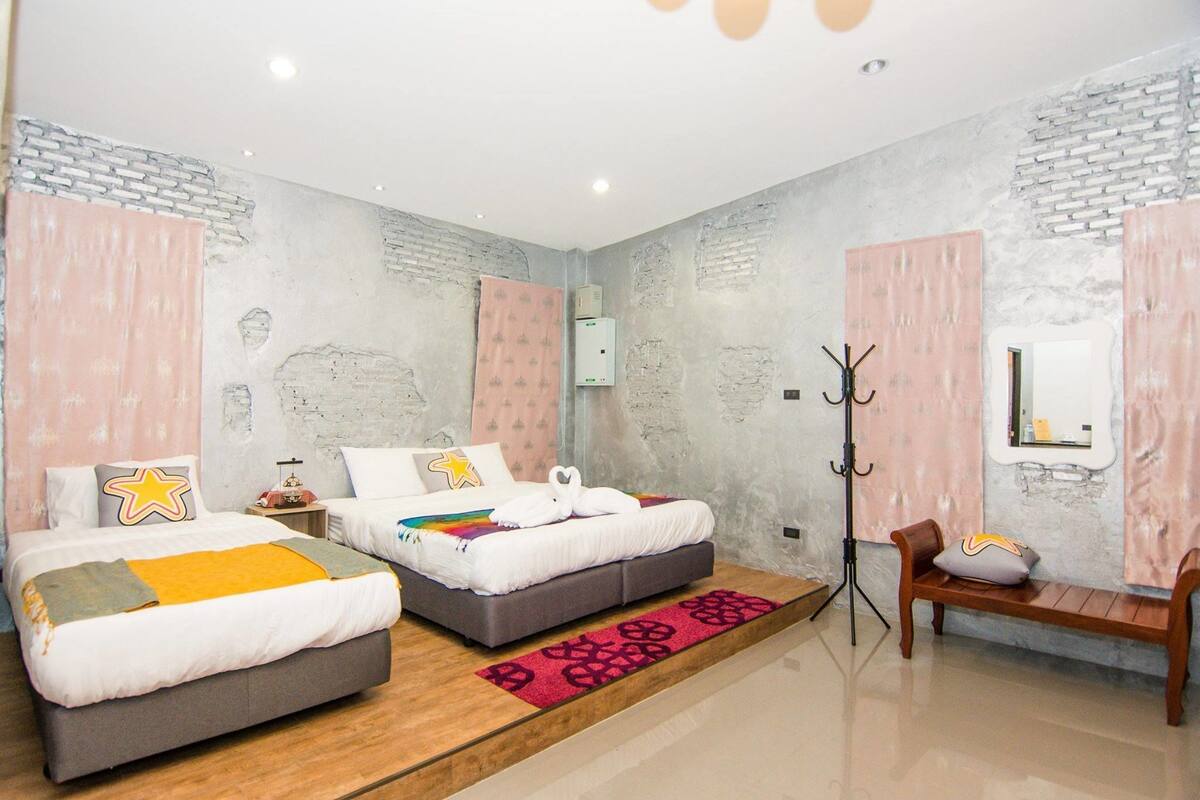 A bedroom with two beds, a bench, a coat rack, and a television.