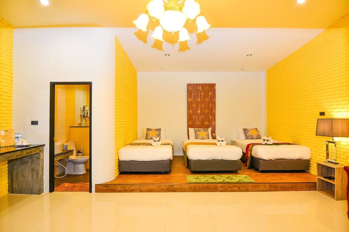 A hotel room with three beds, a bathroom, and a chandelier.