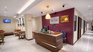 A hotel reception area with a wooden reception desk, a TV screen, and a sign that reads 'SUB. WOW HOTEL.' - Subwow Hostel (Bandung)