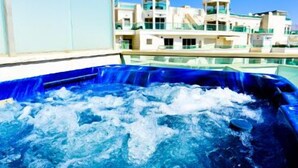 A hot tub on a balcony with a view of a modern building with multiple balconies and a clear blue sky. - La Palmora Suites (Eilat)
