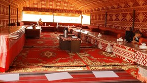 A traditional room with patterned carpets, a central table, and seating arrangements.