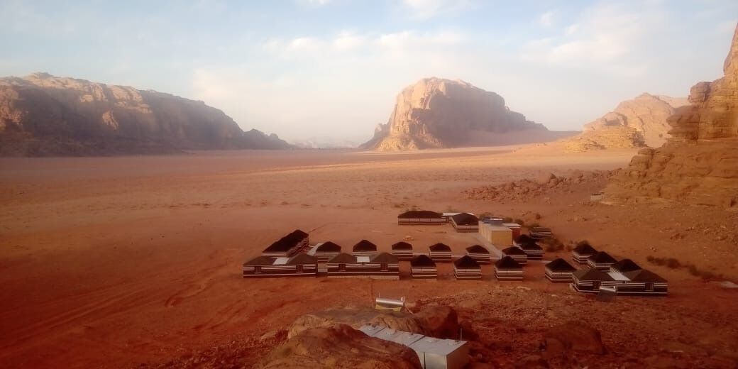 A desert landscape with a row of tents arranged in a line.